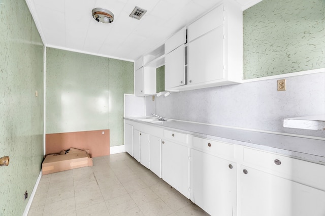 kitchen with white cabinetry, sink, and ornamental molding