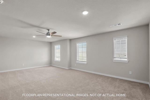 empty room with ceiling fan, light carpet, and a textured ceiling