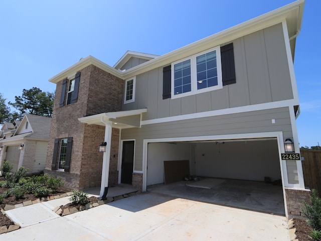 22435 Birchfield Grove Ln, New Caney, TX 77357 - view of front of home with board and batten siding, an attached garage, concrete driveway, and brick siding