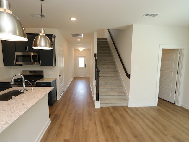 22435 Birchfield Grove Ln, New Caney, TX 77357 - kitchen featuring stainless steel appliances, dark cabinetry, light wood-style flooring, pendant lighting, and recessed lighting