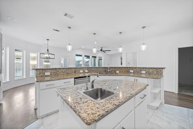 kitchen featuring a kitchen island with sink, visible vents, white cabinets, and a sink