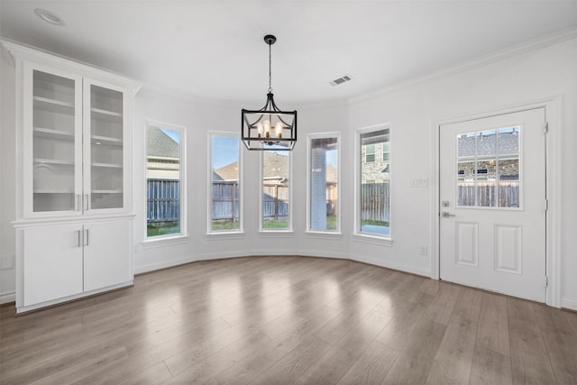 unfurnished dining area featuring ornamental molding, a chandelier, visible vents, and light wood finished floors