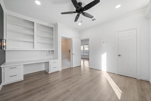 unfurnished bedroom featuring ornamental molding, visible vents, built in desk, and light wood finished floors