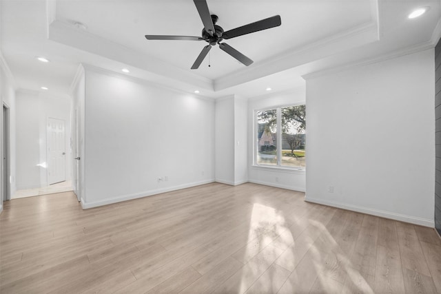 spare room featuring light wood-style floors, a tray ceiling, and crown molding