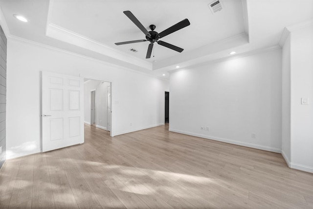 unfurnished room with ornamental molding, light wood-type flooring, a raised ceiling, and visible vents