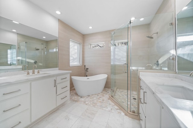 bathroom with a stall shower, two vanities, and a sink