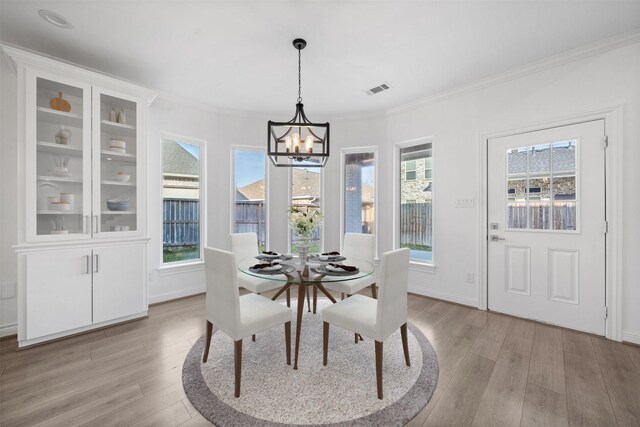 dining room featuring a notable chandelier, a healthy amount of sunlight, visible vents, and light wood-style floors