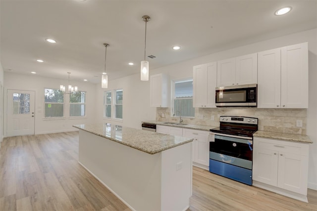 kitchen featuring white cabinets, hanging light fixtures, stainless steel appliances, and a kitchen island