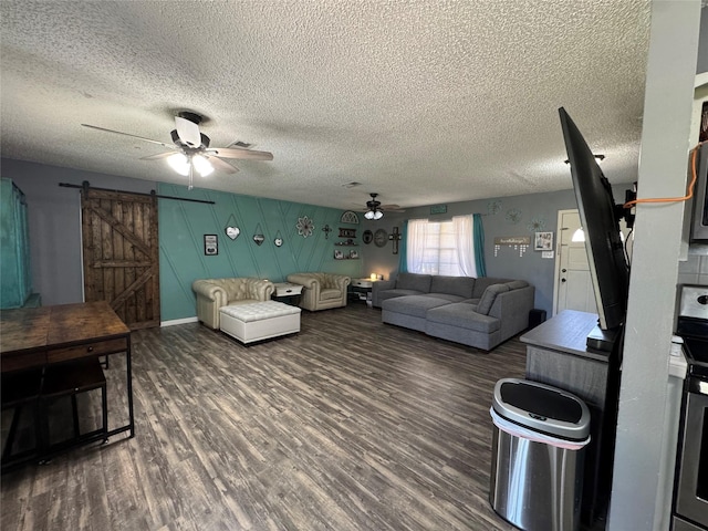 living room with ceiling fan, a textured ceiling, dark hardwood / wood-style flooring, and a barn door