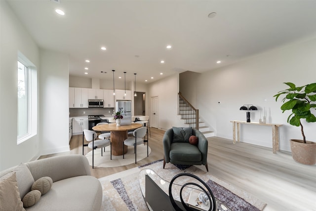 living area with stairway, recessed lighting, baseboards, and light wood-type flooring