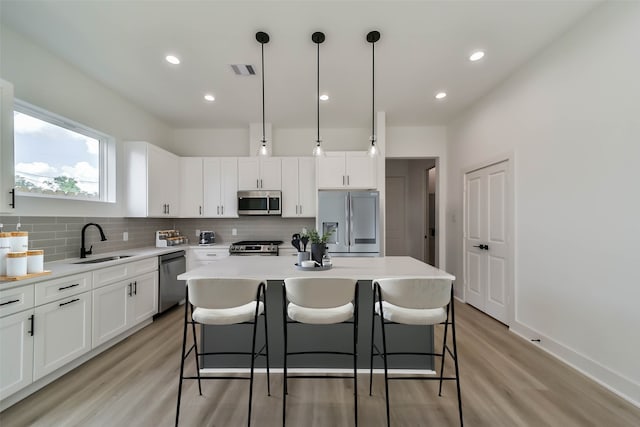 kitchen with a breakfast bar area, visible vents, appliances with stainless steel finishes, tasteful backsplash, and a sink