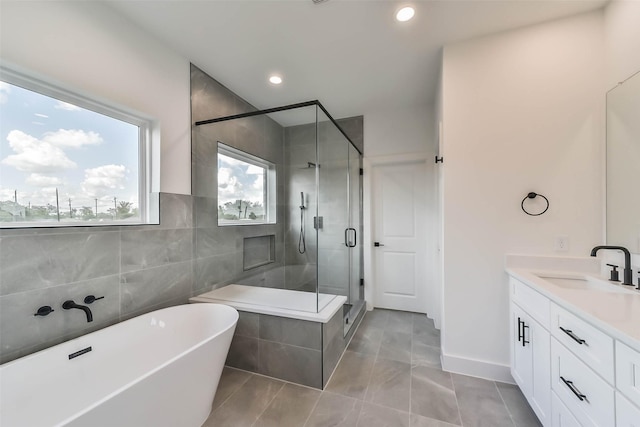 full bathroom featuring vanity, tile walls, recessed lighting, a soaking tub, and a shower stall