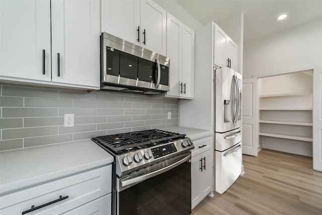 kitchen featuring white cabinets, appliances with stainless steel finishes, light countertops, light wood-type flooring, and tasteful backsplash