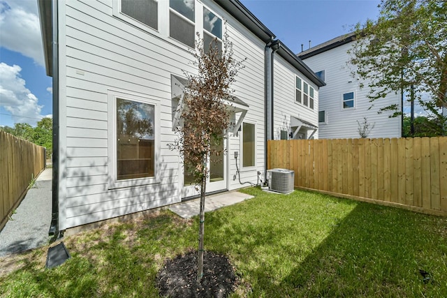 rear view of property with a lawn, central AC, and a fenced backyard