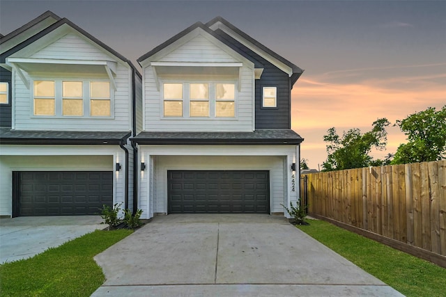 view of front of home with an attached garage, a shingled roof, fence, and driveway