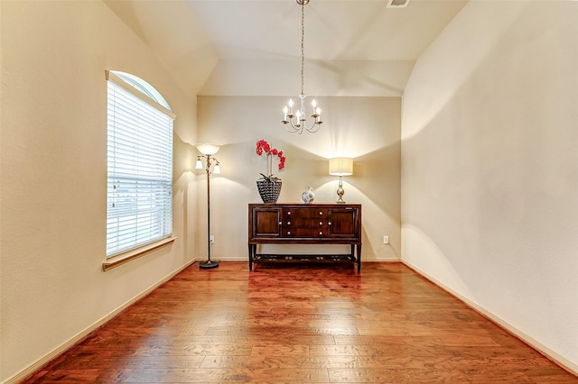 living area featuring hardwood / wood-style flooring, vaulted ceiling, and a notable chandelier