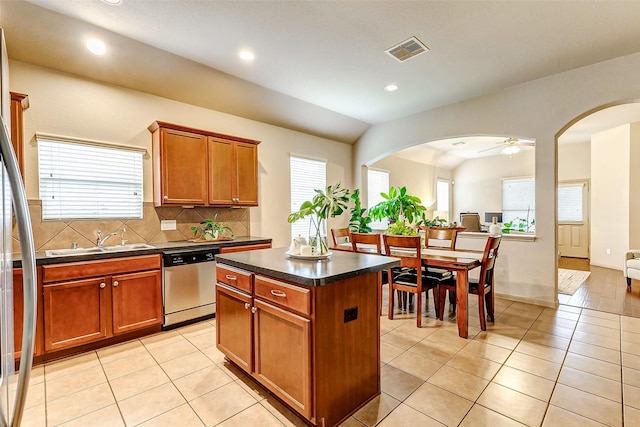 kitchen with stainless steel appliances, decorative backsplash, a center island, light tile patterned floors, and sink