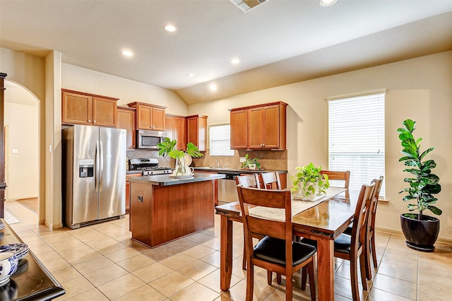 kitchen with a kitchen island, tasteful backsplash, stainless steel appliances, and light tile patterned floors