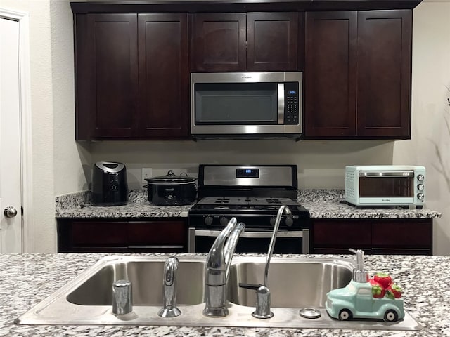 kitchen featuring appliances with stainless steel finishes, light stone counters, and dark brown cabinetry