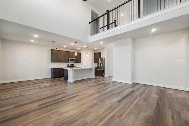 unfurnished living room featuring wood-type flooring and a towering ceiling