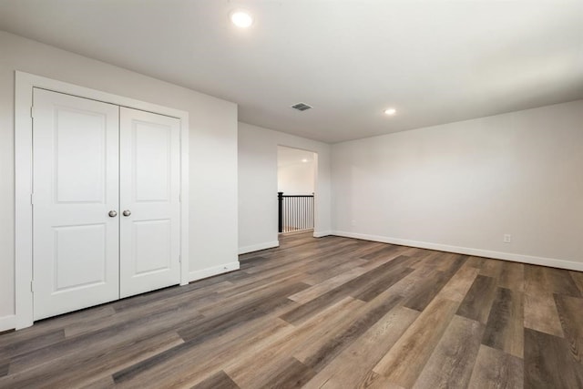 unfurnished bedroom with dark hardwood / wood-style floors and a closet