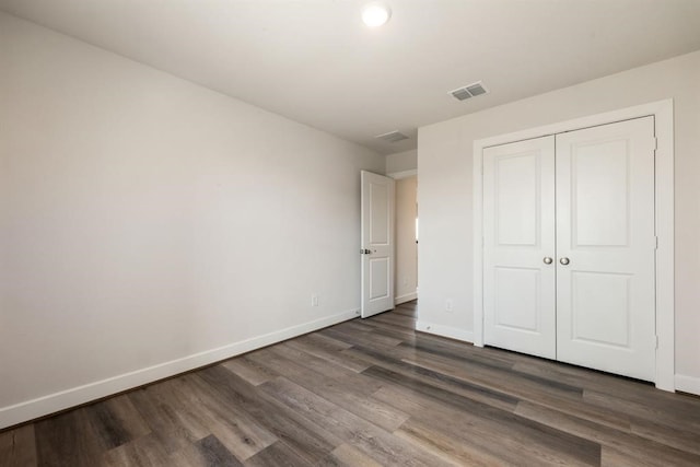 unfurnished bedroom with a closet and dark hardwood / wood-style floors