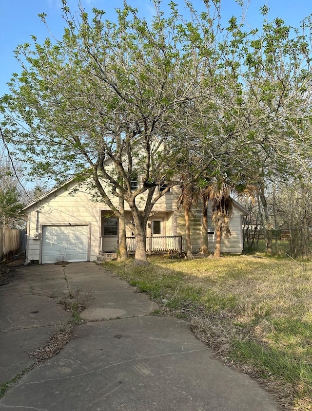 view of front facade featuring an attached garage, concrete driveway, and fence