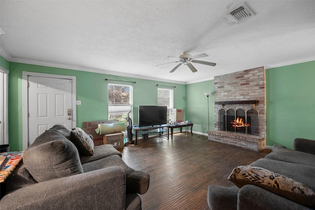 living room with a brick fireplace, a textured ceiling, ceiling fan, dark hardwood / wood-style flooring, and ornamental molding