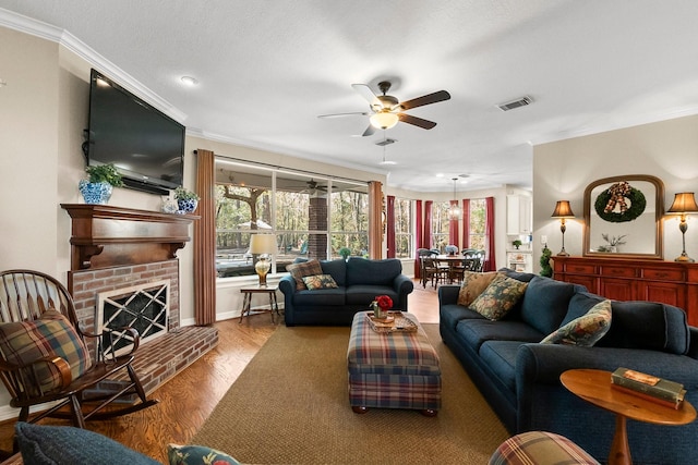 living room with ceiling fan, wood-type flooring, ornamental molding, and a fireplace