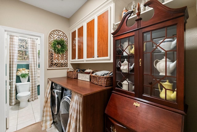 washroom with light tile patterned floors, washer and clothes dryer, and cabinets