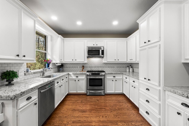 kitchen featuring white cabinetry, sink, appliances with stainless steel finishes, dark hardwood / wood-style floors, and decorative backsplash