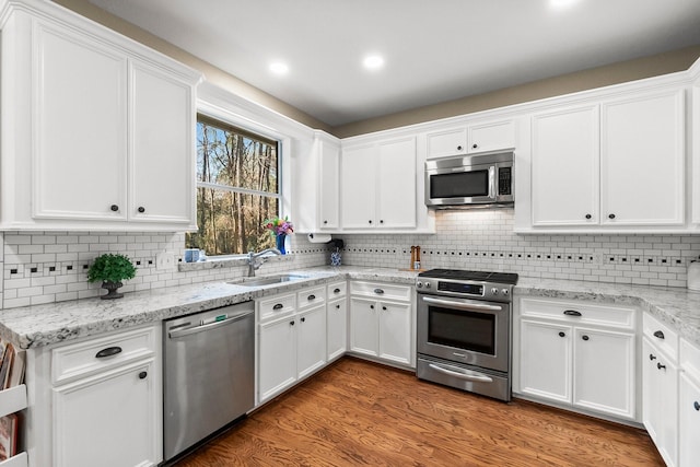 kitchen featuring sink, hardwood / wood-style flooring, white cabinetry, and stainless steel appliances