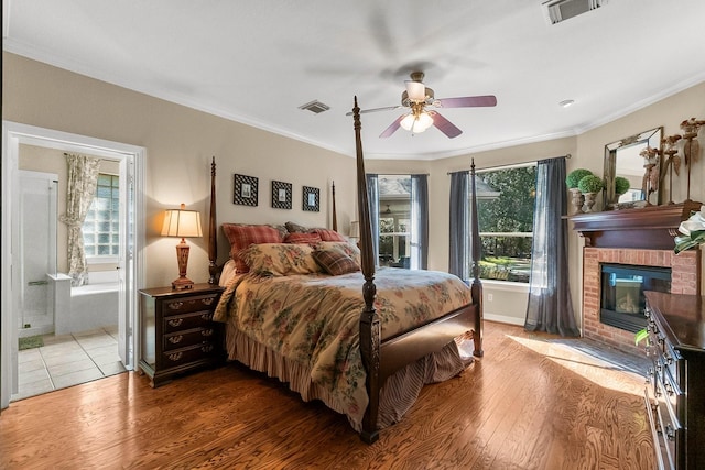 bedroom with ensuite bath, hardwood / wood-style flooring, crown molding, and a fireplace