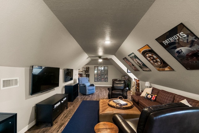 home theater room featuring vaulted ceiling, dark hardwood / wood-style floors, and a textured ceiling