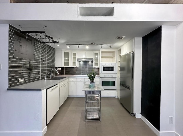 kitchen featuring white dishwasher, glass insert cabinets, freestanding refrigerator, and white cabinetry