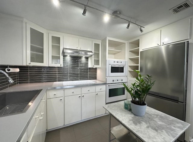 kitchen with visible vents, stainless steel refrigerator, under cabinet range hood, open shelves, and a sink