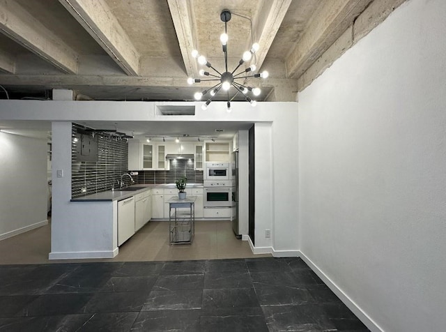 kitchen featuring white dishwasher, white cabinets, dark countertops, glass insert cabinets, and pendant lighting