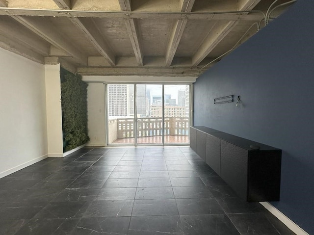 spare room featuring a view of city, dark tile patterned floors, and baseboards