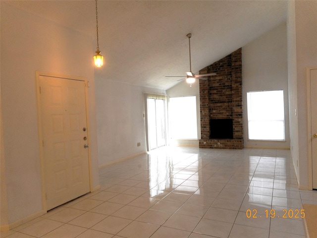 unfurnished living room featuring a fireplace, high vaulted ceiling, a healthy amount of sunlight, and light tile patterned floors