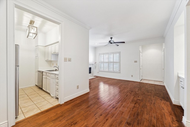 interior space featuring sink, light wood-type flooring, white cabinetry, stainless steel appliances, and ceiling fan