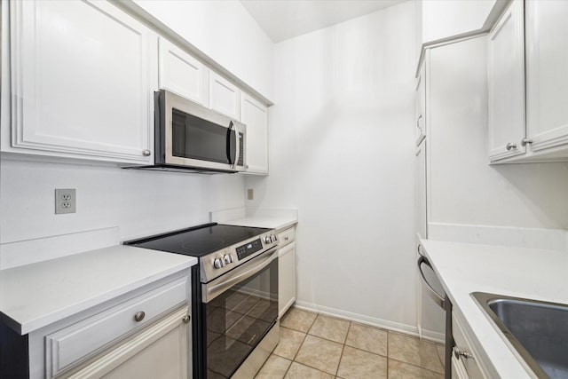 kitchen featuring light tile patterned floors, sink, stainless steel appliances, and white cabinets