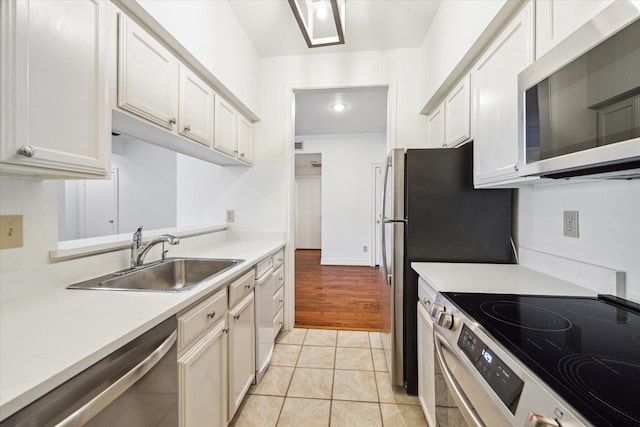 kitchen featuring sink, appliances with stainless steel finishes, white cabinetry, and light tile patterned flooring