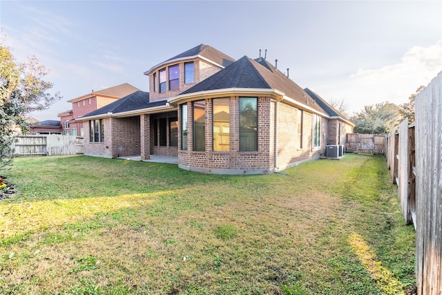 back of house featuring brick siding, central AC, a patio area, a yard, and a fenced backyard