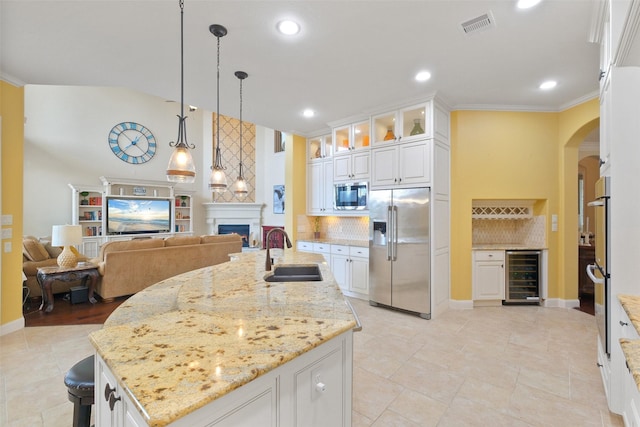 kitchen featuring sink, beverage cooler, white cabinetry, stainless steel appliances, and an island with sink