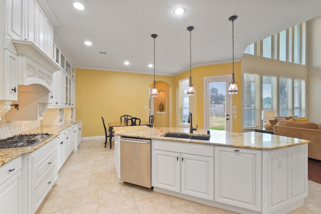 kitchen featuring stainless steel appliances, decorative light fixtures, sink, white cabinetry, and a kitchen island with sink