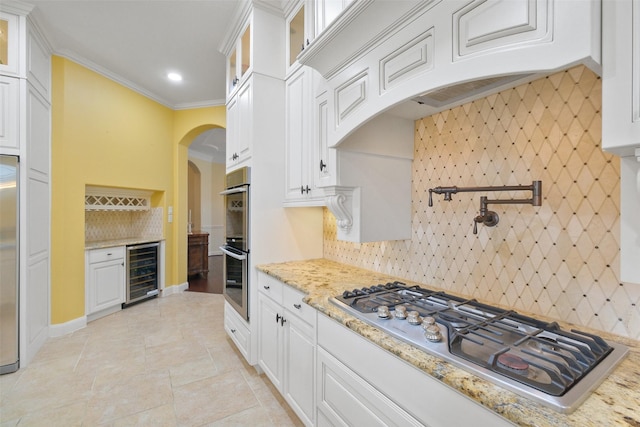 kitchen with wine cooler, stainless steel appliances, white cabinets, and light stone counters