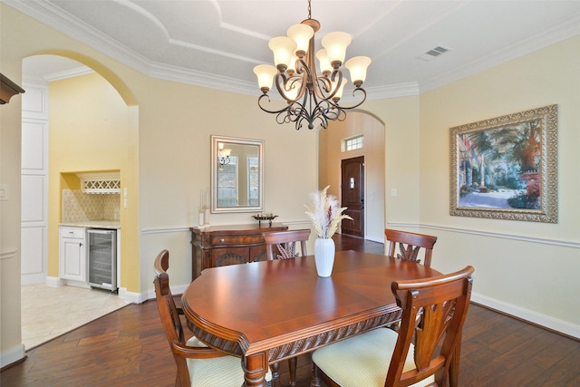 dining space with bar area, dark wood-type flooring, beverage cooler, and ornamental molding