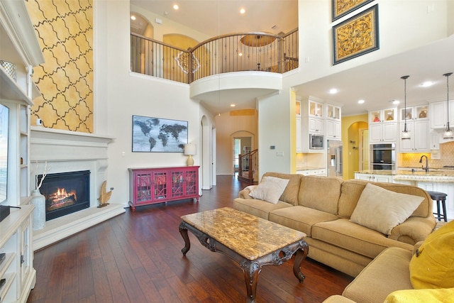 living room with dark hardwood / wood-style flooring, a high ceiling, and sink