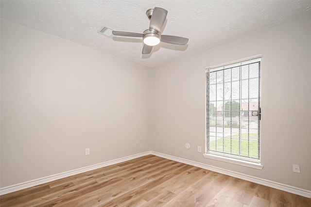 spare room with baseboards, ceiling fan, a textured ceiling, and light wood finished floors