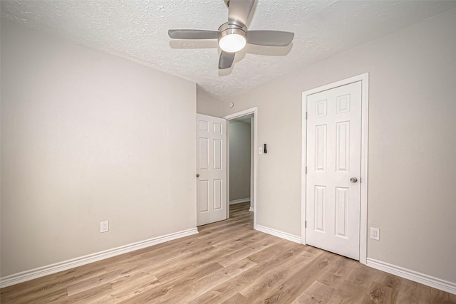 unfurnished bedroom with a ceiling fan, light wood-style flooring, baseboards, and a textured ceiling